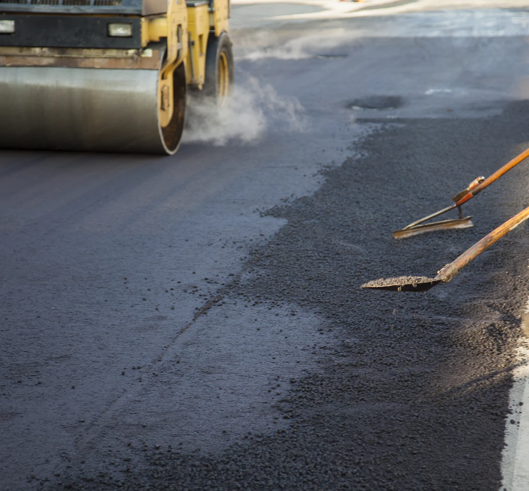 Fresh asphalt being leveled and compacted.